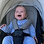 baby, smiling, stroller, blue_pajamas, infant, child, happy, seatbelt, canopy, outdoor, baby_seat, cute, person, baby_clothing, safety_harness, newborn, child_seat, infant_care, transport, baby_face