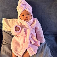 Isabelle joined the competition — help win amazing prizes! baby, child, pink_robe, towel_turban, bed, pillow, blanket, soft_fabric, infant, portrait, indoors, cute, cozy, relaxed, person, smiling, face, skin, fingers, feet