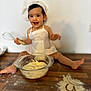 Leya a rejoint le concours — aidez-le/la à gagner de superbes lots ! child, toddler, baby, apron, chef_hat, whisk, mixing_bowl, dough, flour, wooden_table, kitchen, baking, messy, smile, sitting, portrait, indoor, playful, happy, culinary