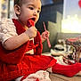 Leya a rejoint le concours — aidez-le/la à gagner de superbes lots ! child, baby, toddler, red_dress, red_socks, lollipop, bow, sitting, indoor, portrait, face, hand, candy, festive, holiday_decor, toy, closeup, cozy, bokeh, skirt
