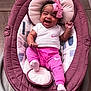 baby, infant, smiling, happy, pink_clothing, white_shirt, headband, bow, baby_rocker, indoor, wooden_floor, footwear, sock, child, person, cute, portrait, relaxing, apparel, joy