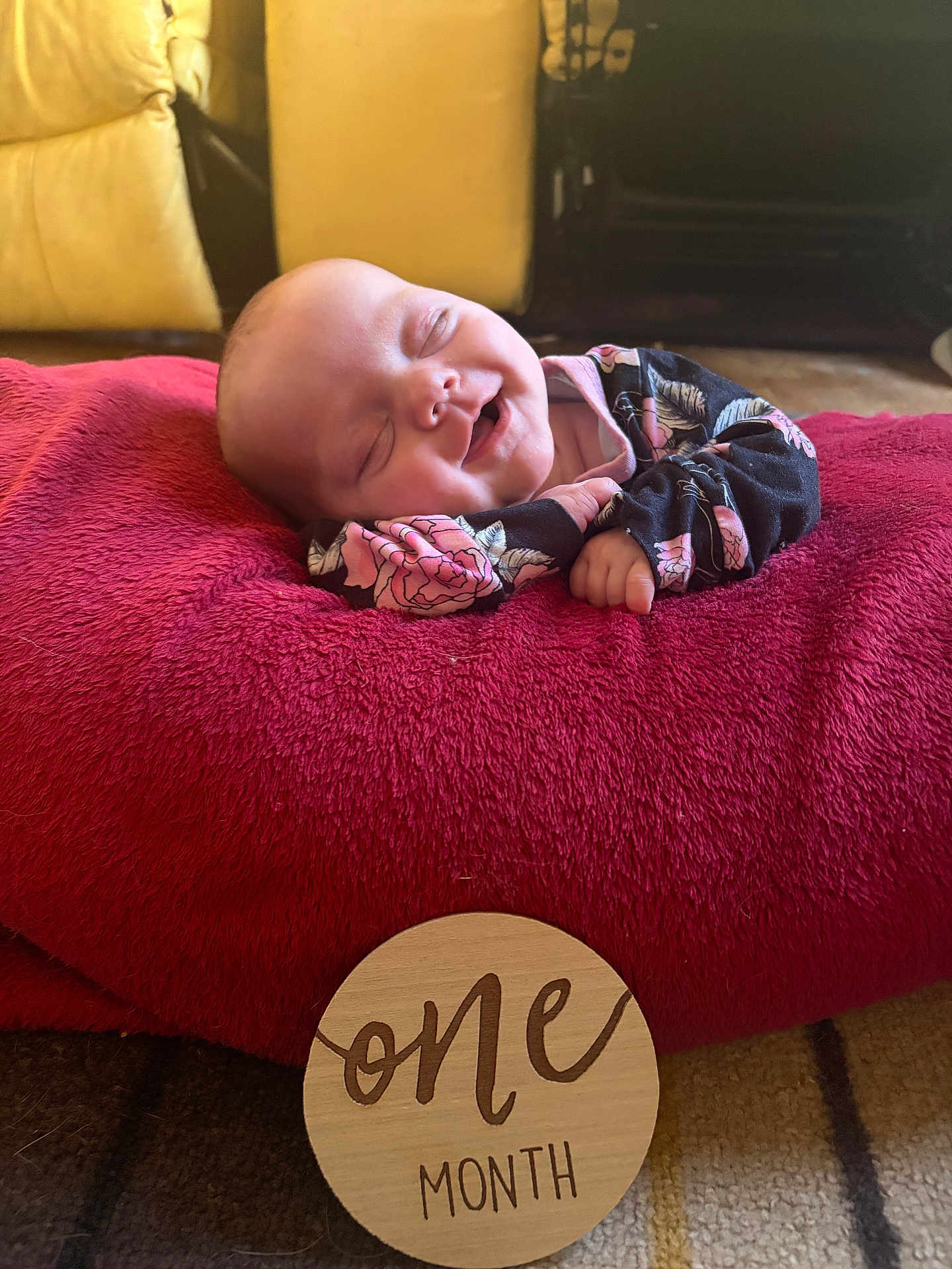 Delilah joined the competition — help win amazing prizes! baby, infant, smiling, sleeping, one_month, cushion, blanket, wooden_sign, floral_clothing, indoor, carpet, cute, resting, young_child, portrait, newborn, soft_texture, happy, peaceful, milestone