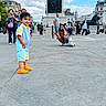 Soham joined the competition — help win amazing prizes! architecture, child, city, clouds, colorful_clothing, landmark, lion_statue, london, monument, nelsons_column, orange_clogs, outdoor, paved_ground, plaza, sky, smiling, toddler, tourists, trafalgar_square, travel