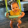 Kevin joined the competition — help win amazing prizes! baby, child, infant, smiling, happy, portrait, face, eyes, indoor, living_room, jumper, baby_swing, hanging_seat, yellow_shirt, colorful, bare_feet, wood_floor, sofa, home, playtime