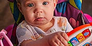 Zoey is registered to the contest to win money with this photo: baby, bodypart, clothing, face, finger, frown, furniture, hand, happy, head, people, person, photography, portrait, rattle, sad, sitting, smile, t_shirt, toy