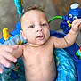 baby, baby_seat, bare_chest, blue_eyes, child, close_up, colorful, curious, cute, expression, indoor, infant, octopus_toy, person, playful, portrait, skin, smiling, toy, young_child
