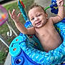 Kobe is registered to the contest to win money with this photo: baby, child, blue_eyes, smiling, happy, arms_up, baby_jumper, toys, outdoor, curly_hair, infant, playful, colorful, plastic, seat, closeup, portrait, cheerful, person, baby_toys