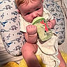 Emmett is registered to the contest to win money with this photo: baby, infant, child, bottle, feeding, bunny, plush_toy, yellow_plush, cushion, blanket, bib, white_clothing, sitting, lying_down, indoors, portrait, face, hands, dinosaur_pattern, cozy