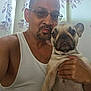 Gwennifer joined the competition — help win amazing prizes! man, dog, french_bulldog, pet, indoor, portrait, glasses, tank_top, holding, face, expression, curtains, window_light, skin, hand, close_up, adult, casual, animal, companionship