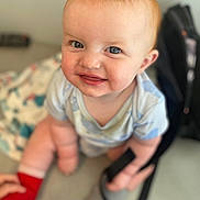 Ava joined the competition — help win amazing prizes! baby, child, smile, blue_eyes, red_sock, onesie, indoor, sitting, happy, cute, face, skin, hair, person, blurry_background, soft_light, chubby_cheeks, toddler, hand, footwear