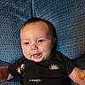 Atlas joined the competition — help win amazing prizes! baby, infant, child, portrait, smiling, tongue_out, lying_down, blue_cushion, black_clothing, sun_pattern, face, eyes, hair, skin, indoor, close_up, happy, cute, relaxed, photography