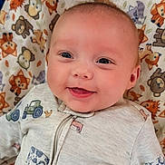 Denny is registered to the contest to win money with this photo: baby, smile, face, infant, onesie, tractor, farm_animals, blanket, animal_pattern, happy, cute, child, portrait, lying_down, indoors, soft_lighting, closeup, head, skin, clothing