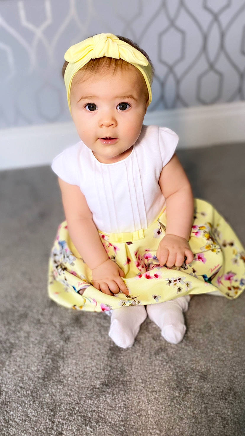 Lillie-rose is registered to the contest to win money with this photo: baby, baby_toddler_clothing, cap, cheek, child, eye, face, finger, flash_photography, fun, happy, head, human_leg, knee, person, pink, sitting, skin, sleeve, t_shirt