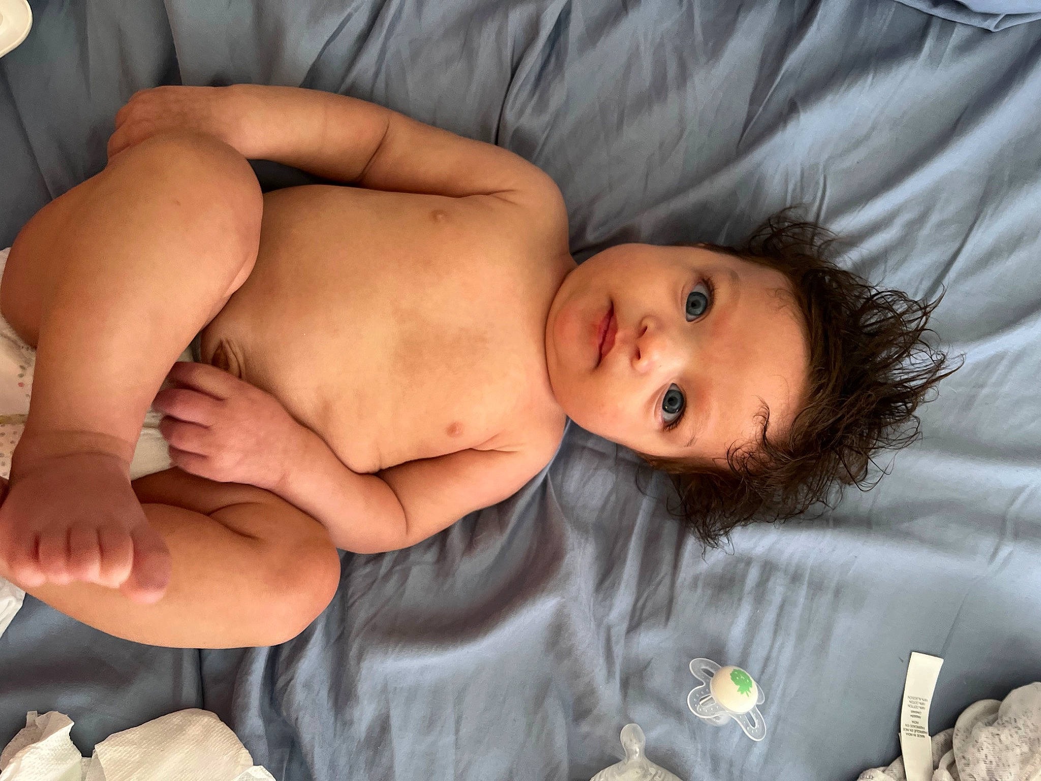 Genevieve is registered to the contest to win money with this photo: abdomen, arm, baby, barechested, cheek, chest, child, comfort, eye, finger, hair, head, human_body, human_leg, linens, mouth, person, skin, stomach, toddler