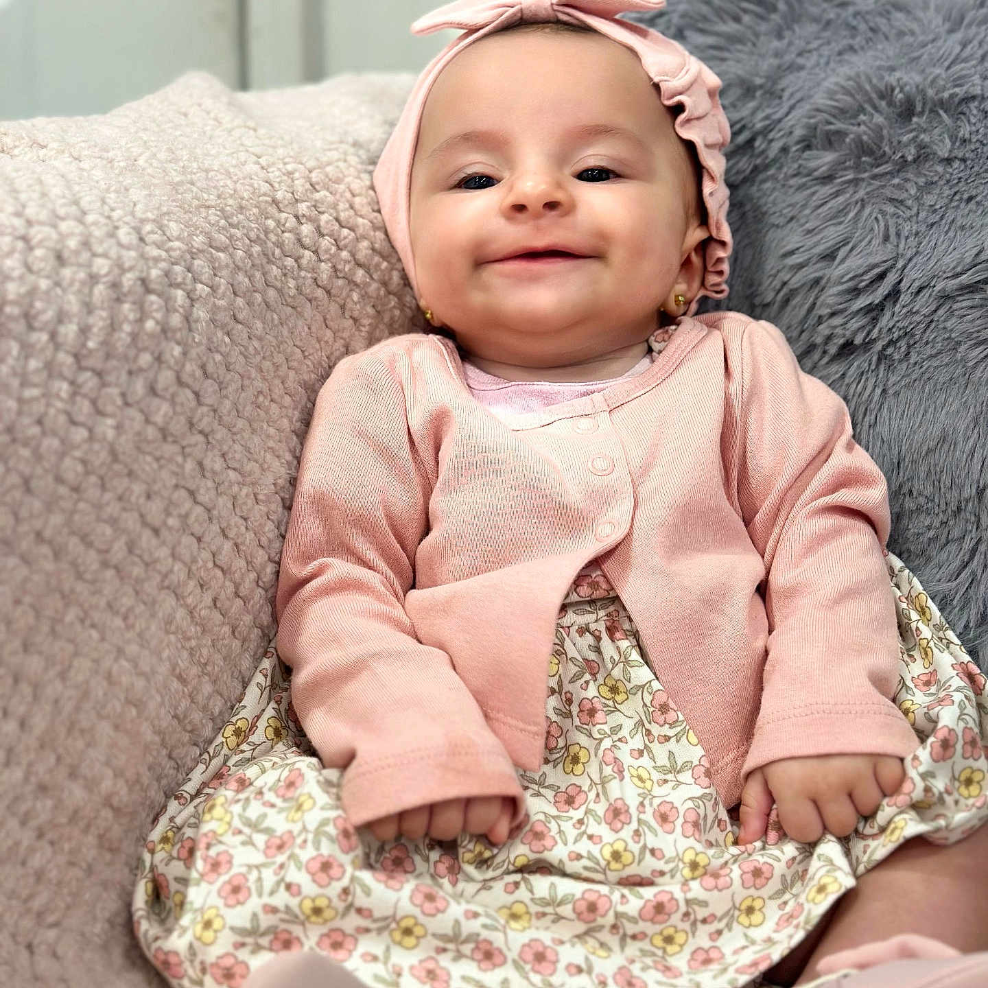 Seline joined the competition — help win amazing prizes! adorable, baby, blanket, child, closeup, cozy, cute, earrings, floral_dress, happy, headband, indoor, infant, pillow, pink_clothing, portrait, seated, small_hands, smiling, soft_texture
