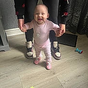 Maisie joined the competition — help win amazing prizes! baby, child, smiling, indoor, flooring, person, holding_hands, pink_clothing, shoes, adult, standing, happy, casual, home, toy, mat, black_pants, sneakers, curtain, wall