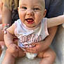 Maisie is registered to the contest to win money with this photo: baby, smiling, child, sitting, happy, face, person, clothing, sleeveless, jordan, cute, infant, skin, head, eyes, mouth, hand, adult, holding, blurred_background