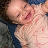 Willow is registered to the contest to win money with this photo: toddler, child, smiling, curly_hair, pink_shirt, koala_print, blanket, blue_blanket, happy, lying_down, baby, indoor, cute, portrait, closeup, infant, person, skin, hand, face