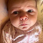 Mercy joined the competition — help win amazing prizes! baby, infant, newborn, face, eyes, cheeks, onesie, heart_pattern, pink, zipper, portrait, closeup, lying_down, bed, blanket, arm, tattoo, soft_lighting, curious_expression, skin