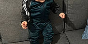 Amir participe au concours pour gagner de l'argent avec cette photo : toddler, child, smile, dimples, tracksuit, sneakers, white_shoes, couch, living_room, furniture, happy, person, indoors, hair, face, footwear, standing, apparel, sporty, cute