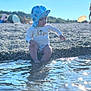 Amir a rejoint le concours — aidez-le/la à gagner de superbes lots ! toddler, child, beach, water, pebbles, sunhat, blue, summer, outdoor, nature, sunlight, reflection, playing, casual_clothing, sitting, daylight, people, background, scenery, vacation