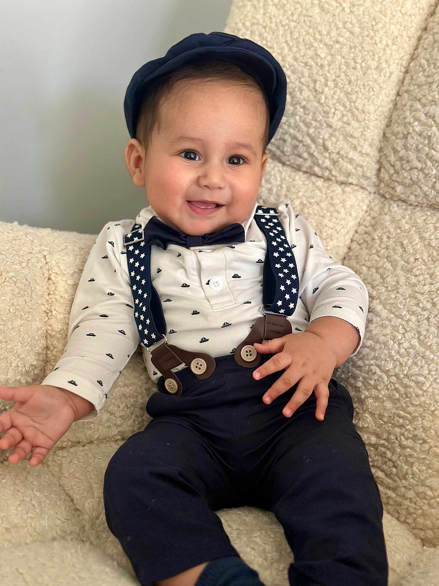 Mathias joined the competition — help win amazing prizes! baby, child, smiling, hat, bow_tie, suspenders, shirt, pants, sitting, indoor, cozy, chair, cute, portrait, happy, young, fashion, clothing, face, person