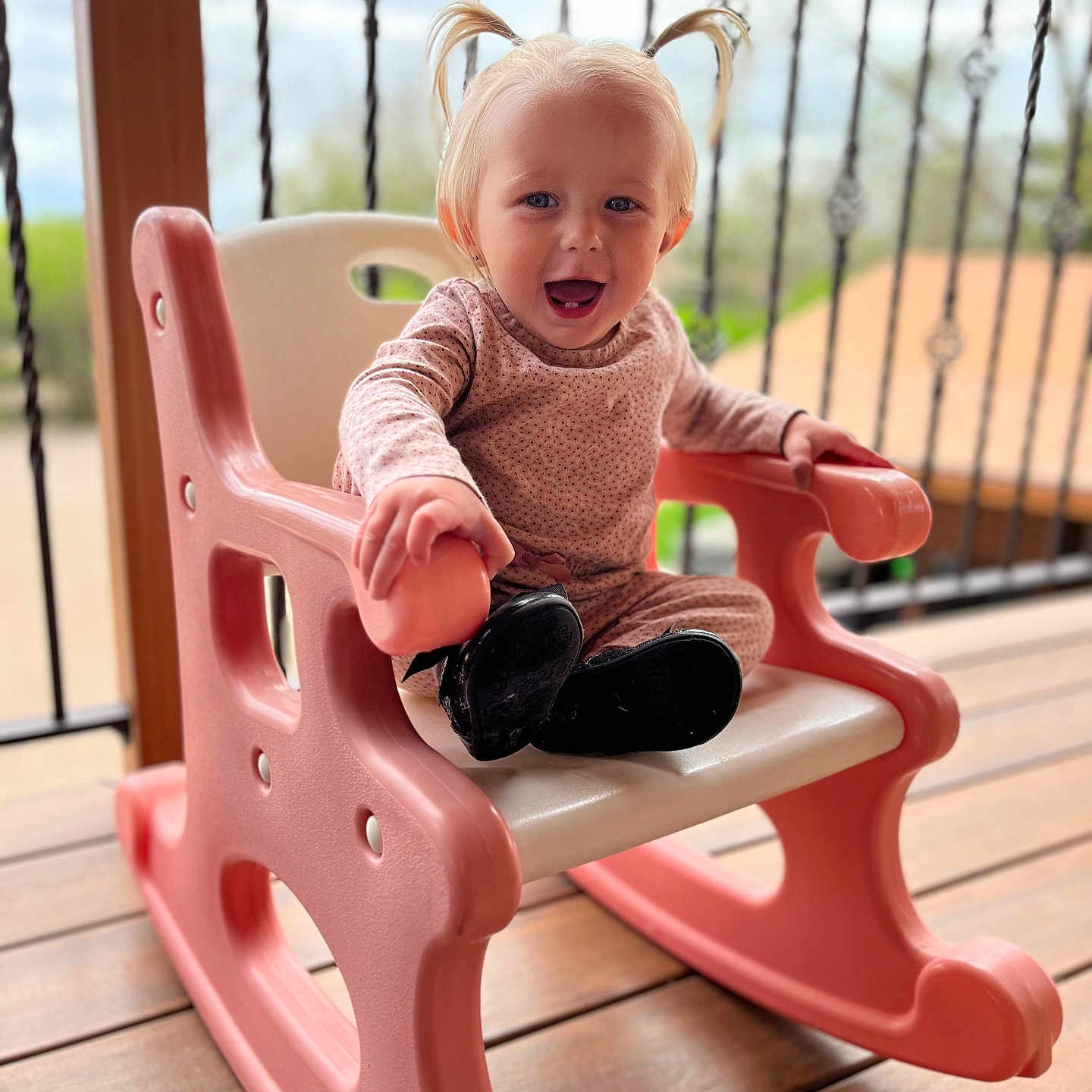 Pais is registered to the contest to win money with this photo: balcony, black_boots, blonde_hair, child, cute, depth_of_field, face, happy, outdoor, person, pigtails, pink, plastic_chair, playtime, portrait, rocking_chair, seat, smiling, toddler, wooden_deck