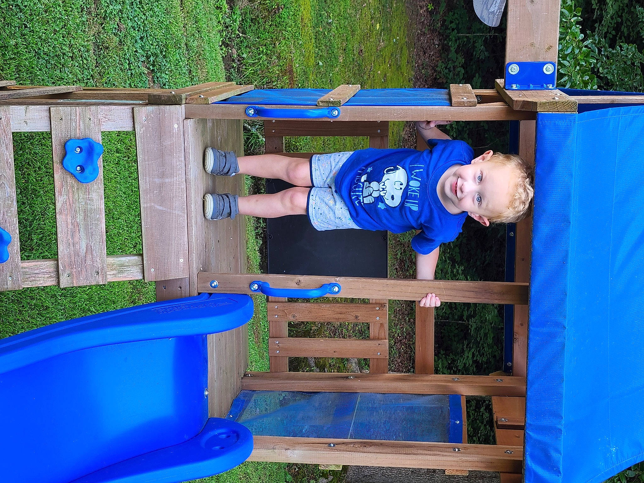 Brian is registered to the contest to win money with this photo: baby_toddler_clothing, balance, blue, child, electric_blue, fun, grass, joy, leisure, outdoor_furniture, outdoor_play_equipment, person, plant, play, playground, recreation, shorts, smile, t_shirt, toddler