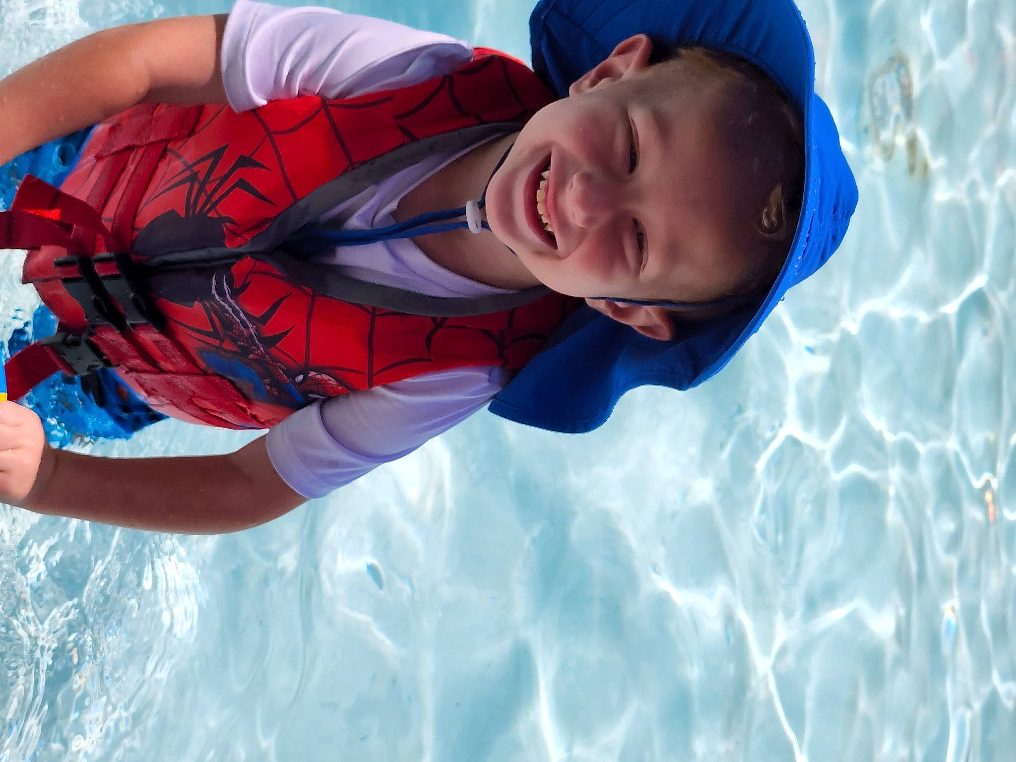 Brian is registered to the contest to win money with this photo: azure, blue, child, elbow, electric_blue, fun, happy, hat, headgear, joy, leisure, lifejacket, light, person, personal_protective_equipment, recreation, sky, smile, summer, swimming_pool