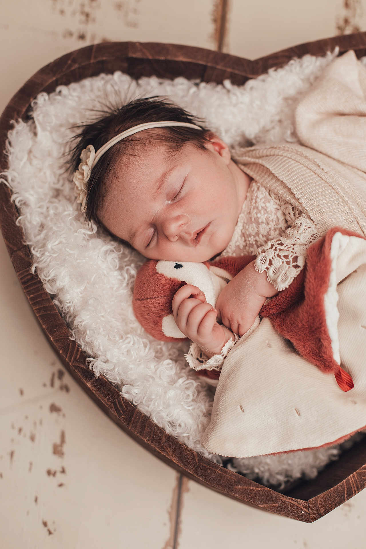 Garance a rejoint le concours — aidez-le/la à gagner de superbes lots ! baby, sleeping, infant, plush_toy, heart_shaped_basket, wooden_basket, lace_clothing, soft_blanket, cozy, cute, child, newborn, headband, hand, face, indoors, peaceful, warm_colors, portrait, resting