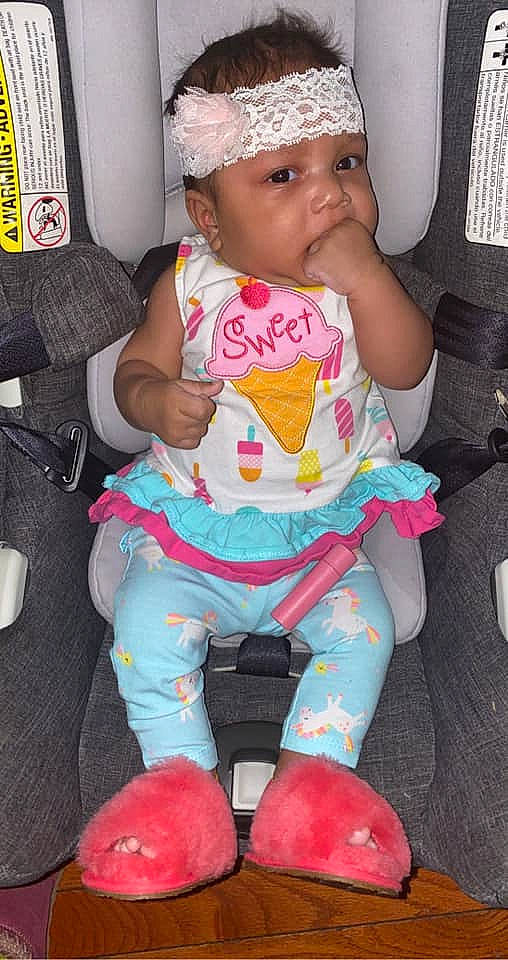 Anika is registered to the contest to win money with this photo: baby, baby_products, baby_toddler_clothing, car_seat, chair, cheek, child, finger, fun, happy, headwear, lap, mouth, nail, person, pink, sitting, skin, sock, thigh