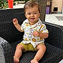 barefoot, casual, chair, child, daylight, face, furniture, happy, nature, outdoor, patio, person, potted_plant, shirt, shorts, sitting, smiling, snack, toddler, wooden_post