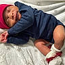 newborn, baby, sleeping, red_hat, navy_blue_clothing, white_blanket, infant, cute, cozy, resting, hands, socks, frills, soft_texture, portrait, indoors, peaceful, warm, child, toddler