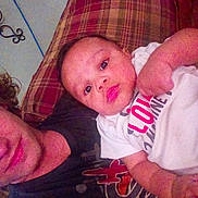 Dallas is registered to the contest to win money with this photo: baby, child, person, couch, plaid, cushion, indoor, shirt, text, face, expression, adult, curly_hair, skin, laying_down, closeup, furniture, decor, wall, home