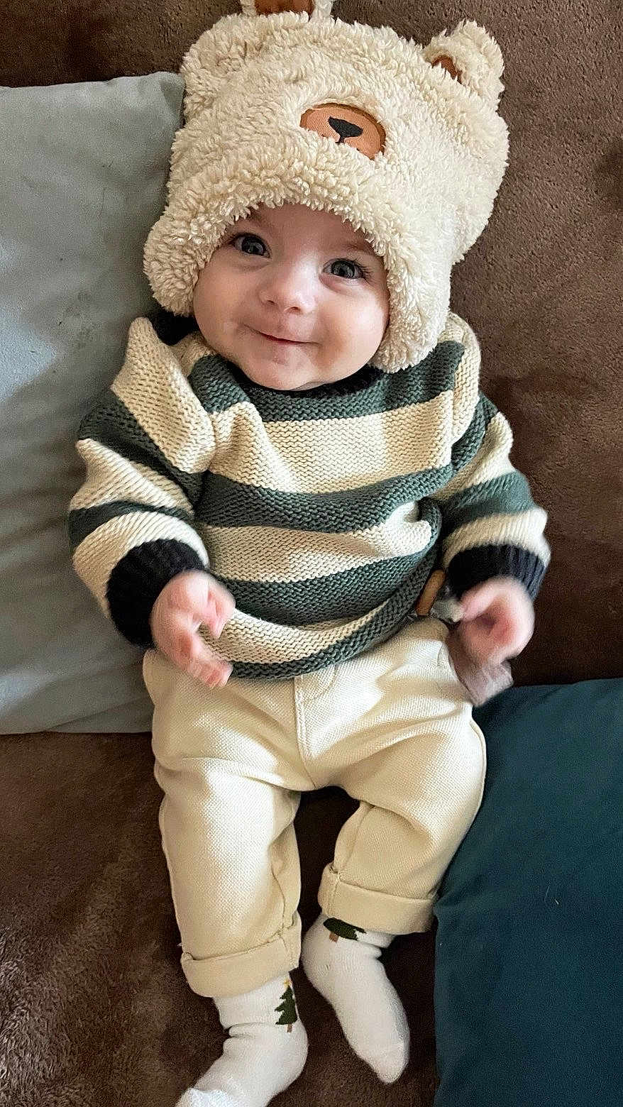 Mylan a rejoint le concours — aidez-le/la à gagner de superbes lots ! baby, child, smile, hat, bear_hat, striped_sweater, pants, socks, couch, cushion, indoor, cute, portrait, happy, infant, person, clothing, cozy, seated, young_child