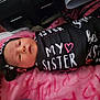 baby, newborn, blanket, headband, bow, sleeping, face, clothing, pink, black, white, text, soft, indoor, child, person, swaddled, cute, resting, infant