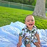Moses is registered to the contest to win money with this photo: toddler, child, smiling, laughing, outdoor, blanket, grass, tree, nature, greenery, happy, portrait, clothing, shorts, shirt, barefoot, sunlight, park, person, baby
