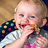baby, child, infant, smiling, happy, blue_eyes, blond_hair, portrait, close_up, eating, food, messy_face, hands, sitting, high_chair, polka_dots, indoor, colorful, bow, shirt