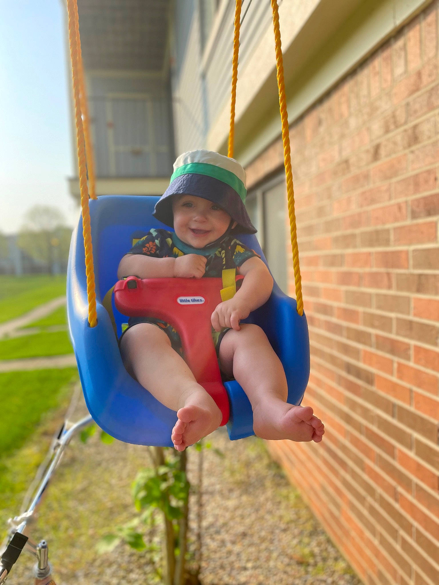 Landry joined the competition — help win amazing prizes! baby_toddler_clothing, brick, brickwork, city, electric_blue, eye, fun, grass, happy, hat, headwear, joy, leisure, outdoor_play_equipment, person, recreation, shorts, sky, smile, swing