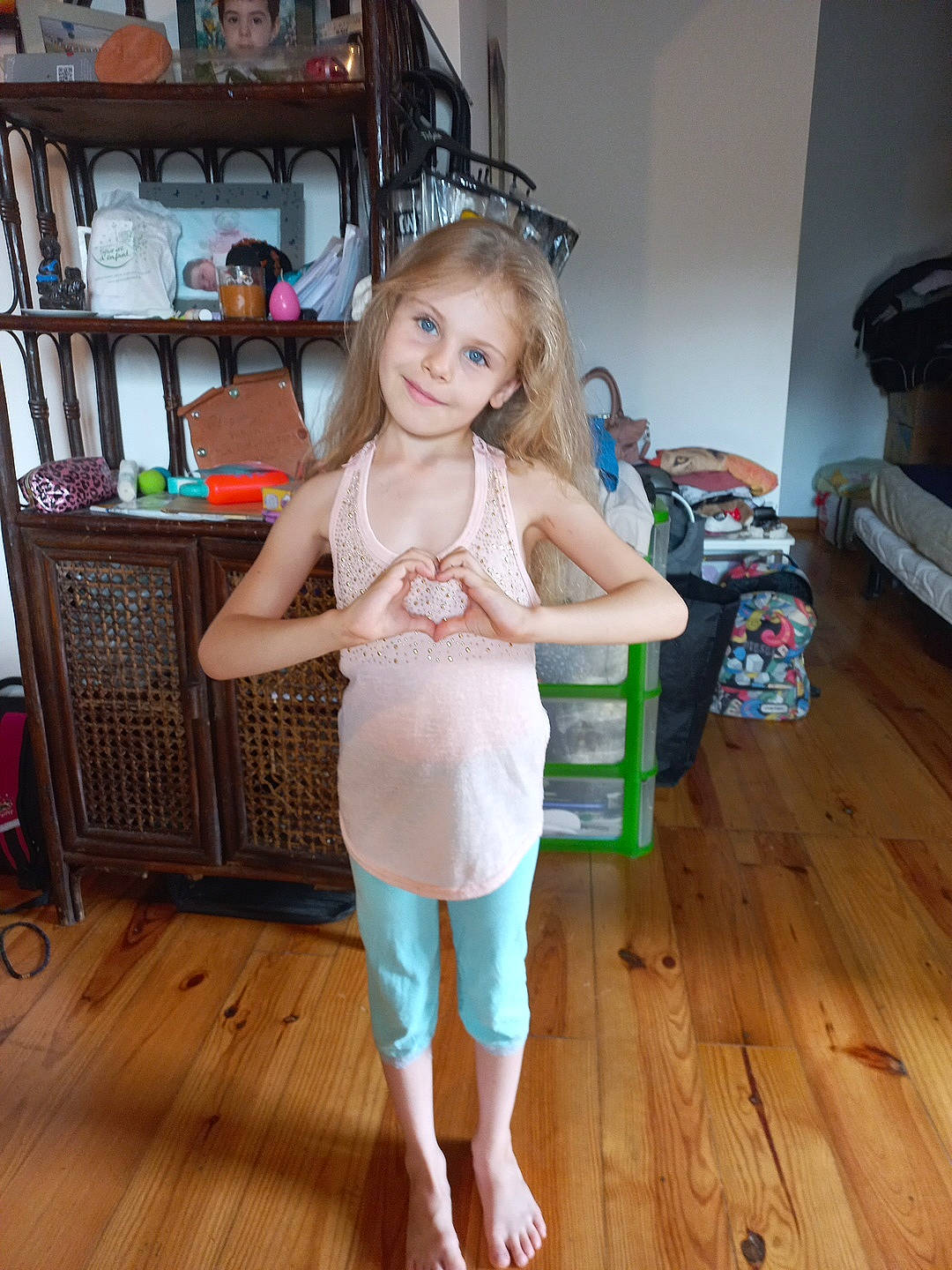 Louane a rejoint le concours — aidez-le/la à gagner de superbes lots ! bookcase, chair, floor, flooring, foot, happy, hardwood, human_leg, joy, knee, laminate_flooring, leg, long_hair, person, shelf, smile, standing, thigh, toddler, waist