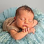 newborn, baby, sleeping, basket, knitted_outfit, blue_fabric, curly_texture, soft, cozy, peaceful, portrait, infant, resting, cute, hands, face, skin, head, closed_eyes, indoors
