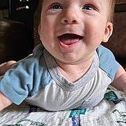 Jaxon joined the competition — help win amazing prizes! baby, smiling, indoor, blanket, face, happy, child, toddler, clothing, blue_shirt, furniture, couch, head, portrait, person, closeup, infant, expression, home, cheerful