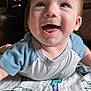 baby, smiling, indoor, blanket, face, happy, child, toddler, clothing, blue_shirt, furniture, couch, head, portrait, person, closeup, infant, expression, home, cheerful