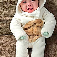 Kayden is registered to the contest to win money with this photo: baby, smiling, onesie, costume, bear_theme, hood, couch, furniture, infant, cute, child, happy, plush, seated, indoor, cozy, clothing, portrait, young, person