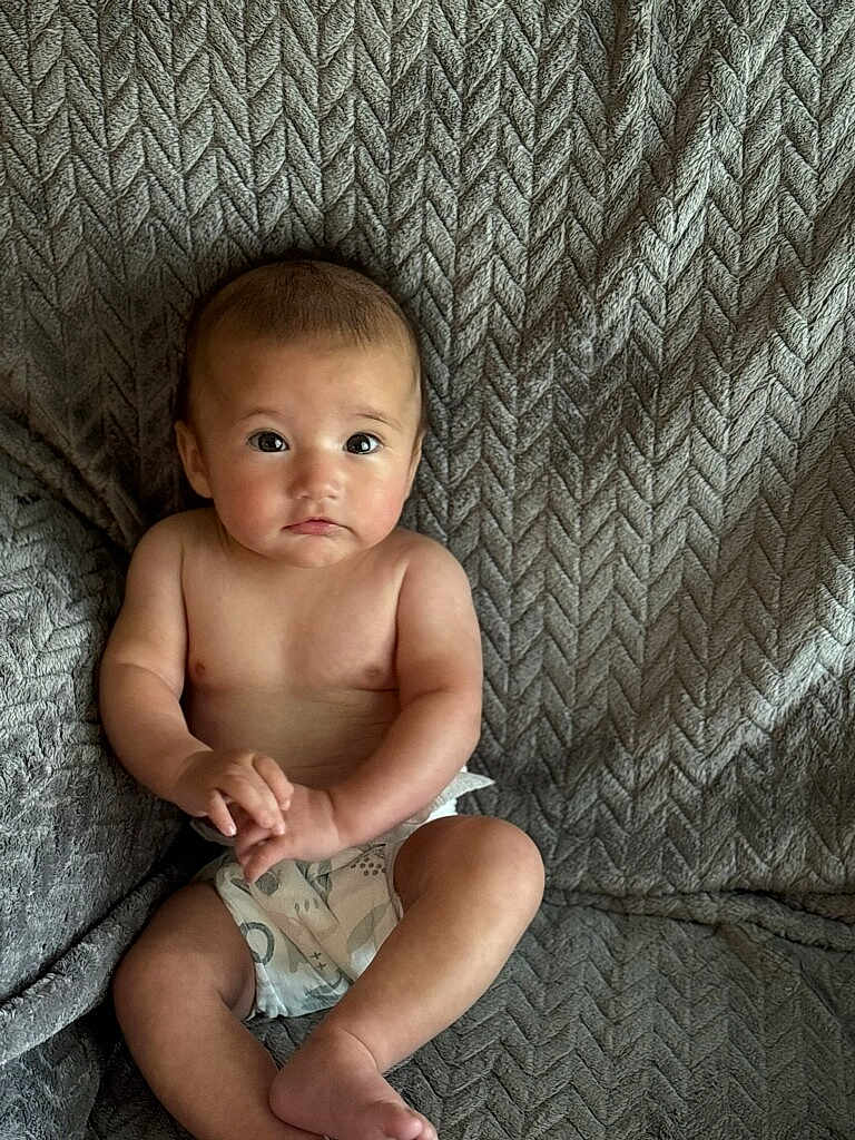 Emery Rose joined the competition — help win amazing prizes! baby, infant, child, diaper, couch, textured_fabric, sitting, curious, hands, feet, skin, indoors, portrait, young_child, expression, soft_light, comfort, cozy, home, casual