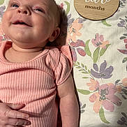 Paisley joined the competition — help win amazing prizes! baby, infant, two_months, child, face, portrait, lying_down, pink_outfit, romper, floral_blanket, wooden_sign, milestone_photo, indoors, bed, baby_hand, blue_eyes, looking_at_camera, cute, newborn, photography