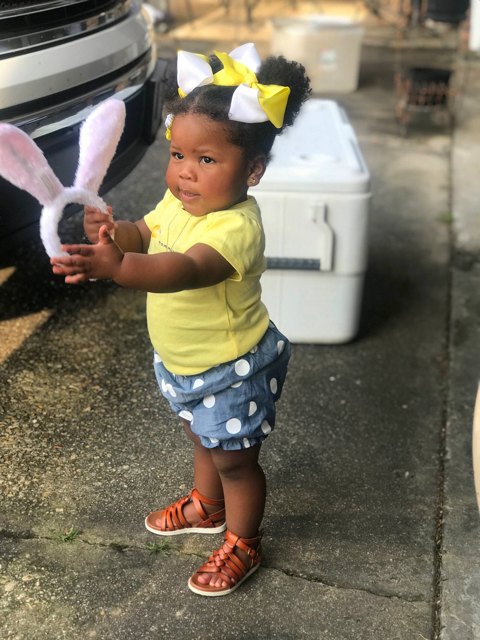 Taliyah is registered to the contest to win money with this photo: automotive_exterior, bumper, child, flip_flops, foot, fun, happy, human_leg, leisure, motor_vehicle, pedestrian, person, road, sandal, shoe, slipper, snapshot, street, toddler, vehicle_door