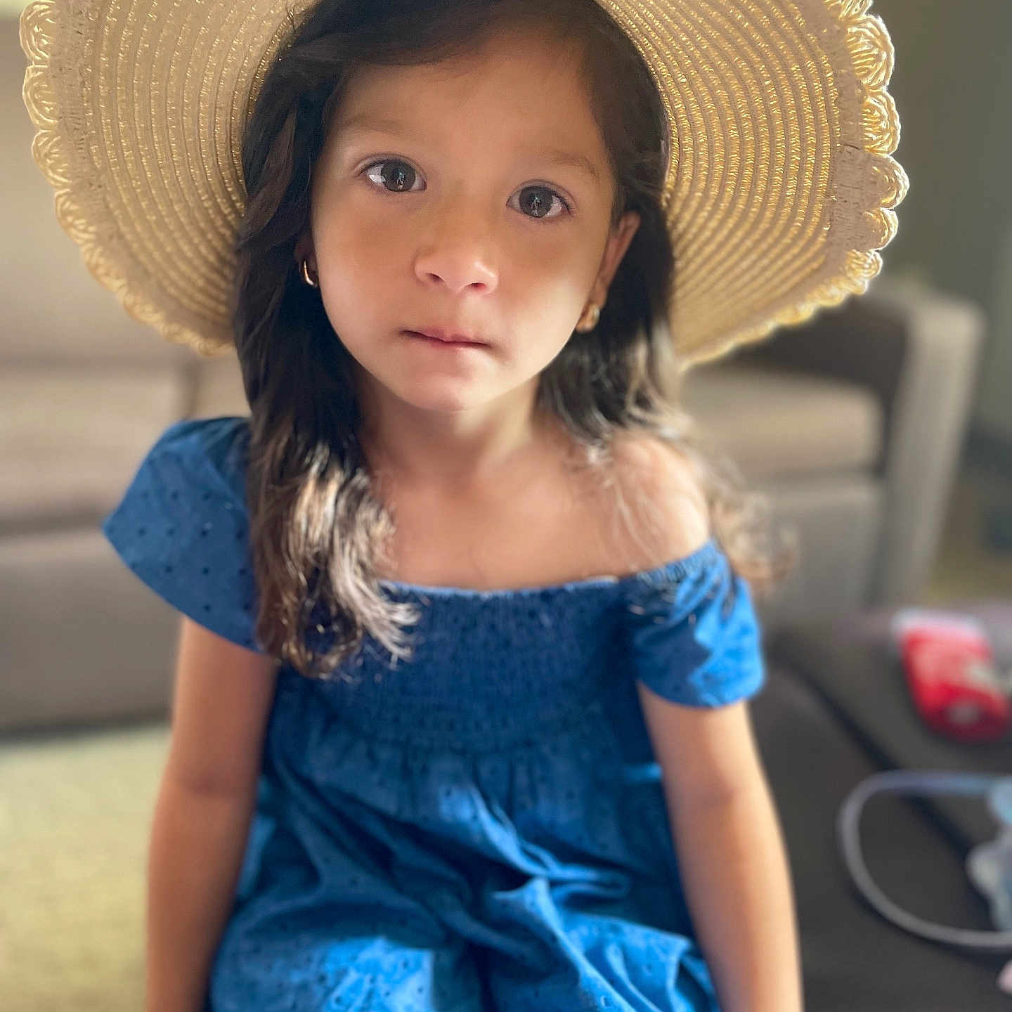 Mira is registered to the contest to win money with this photo: blue_dress, casual_clothing, child, couch, earrings, expression, face, furniture, girl, hat, home, indoor, long_hair, natural_light, person, portrait, sitting, soft_focus, straw_hat, young