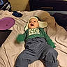 baby, bed, blanket, child, clothing, cozy, green_mittens, happy, hat, indoor, infant, nightstand, pants, person, photograph, plush_toys, smile, socks, toy, warm_clothing