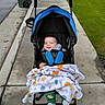 Daniel Moreno joined the competition — help win amazing prizes! baby, blanket, child, curb, footwear, grass, green_pants, happy, hoodie, jacket, outdoor, person, pumpkin_pattern, sidewalk, smile, socks, stroller, trash_bin, tree, urban